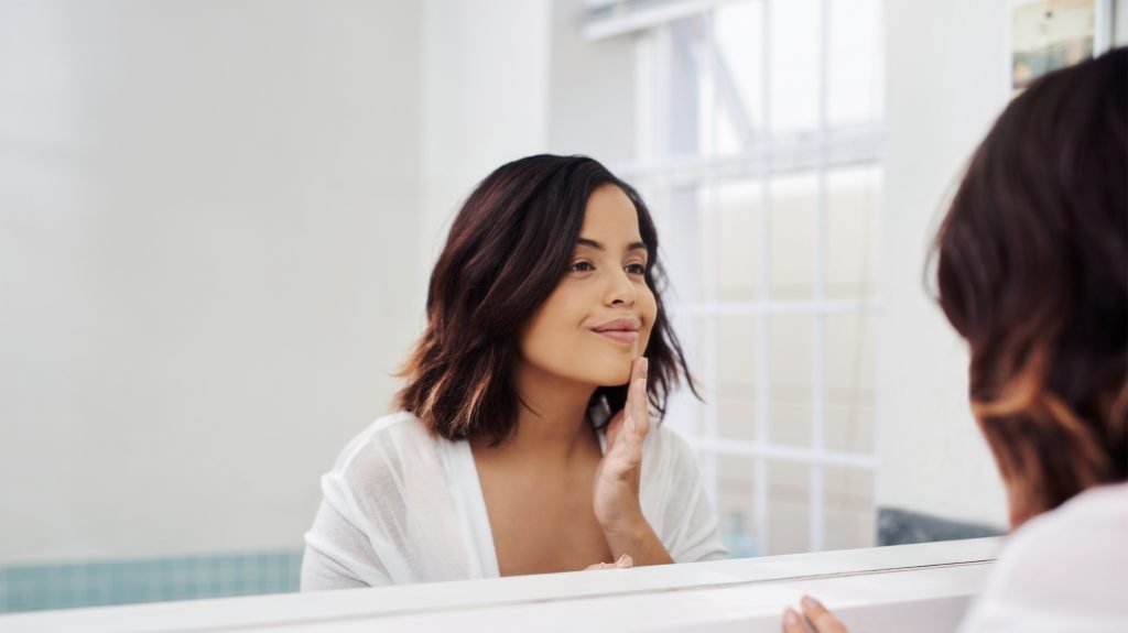 woman smiling into mirror