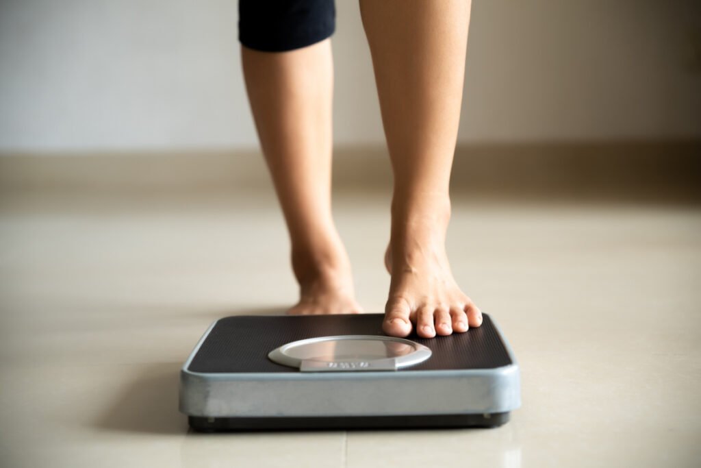 Woman stepping on scale after massive weight loss