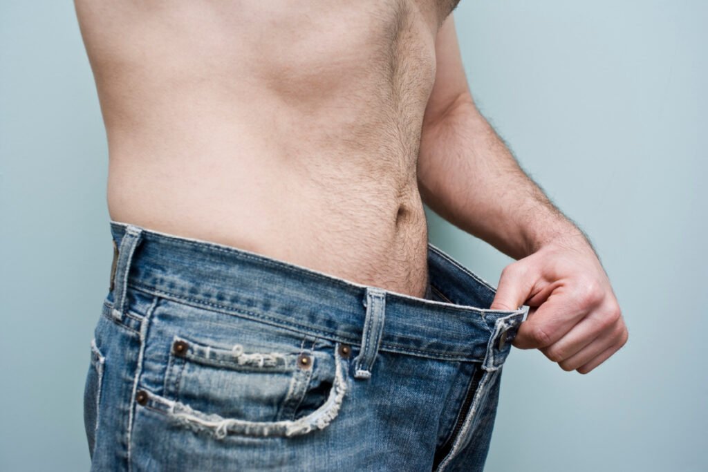 Man holding large jeans after massive weight loss